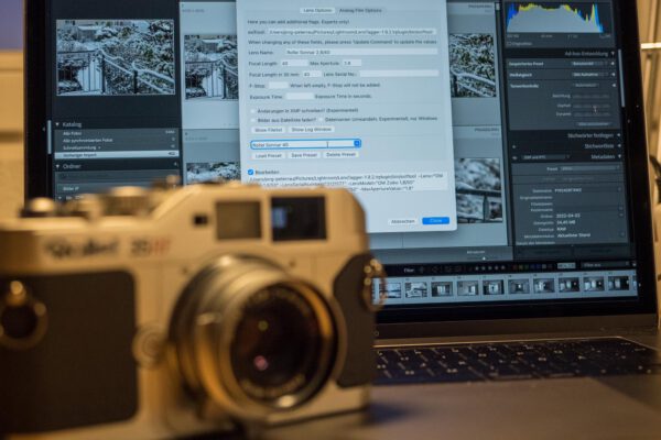 analoge Kamera (Rollei 35RF) vor Computer, auf dem das Plugin LensTagger für Lightroom läuft