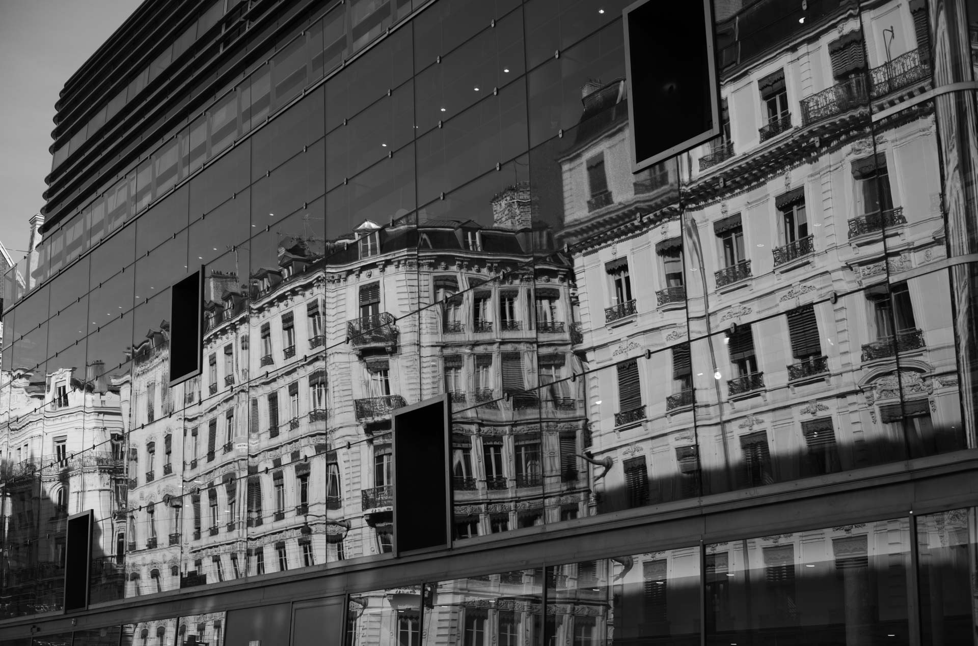 Beispielfoto mit Thypoch Simera 50/1.4: eine Reihe prächtiger Wohnhäuser aus dem 19. Jahrhundert, gespiegelt in einer modernen Glasfassade, Lyon, Frankreich.