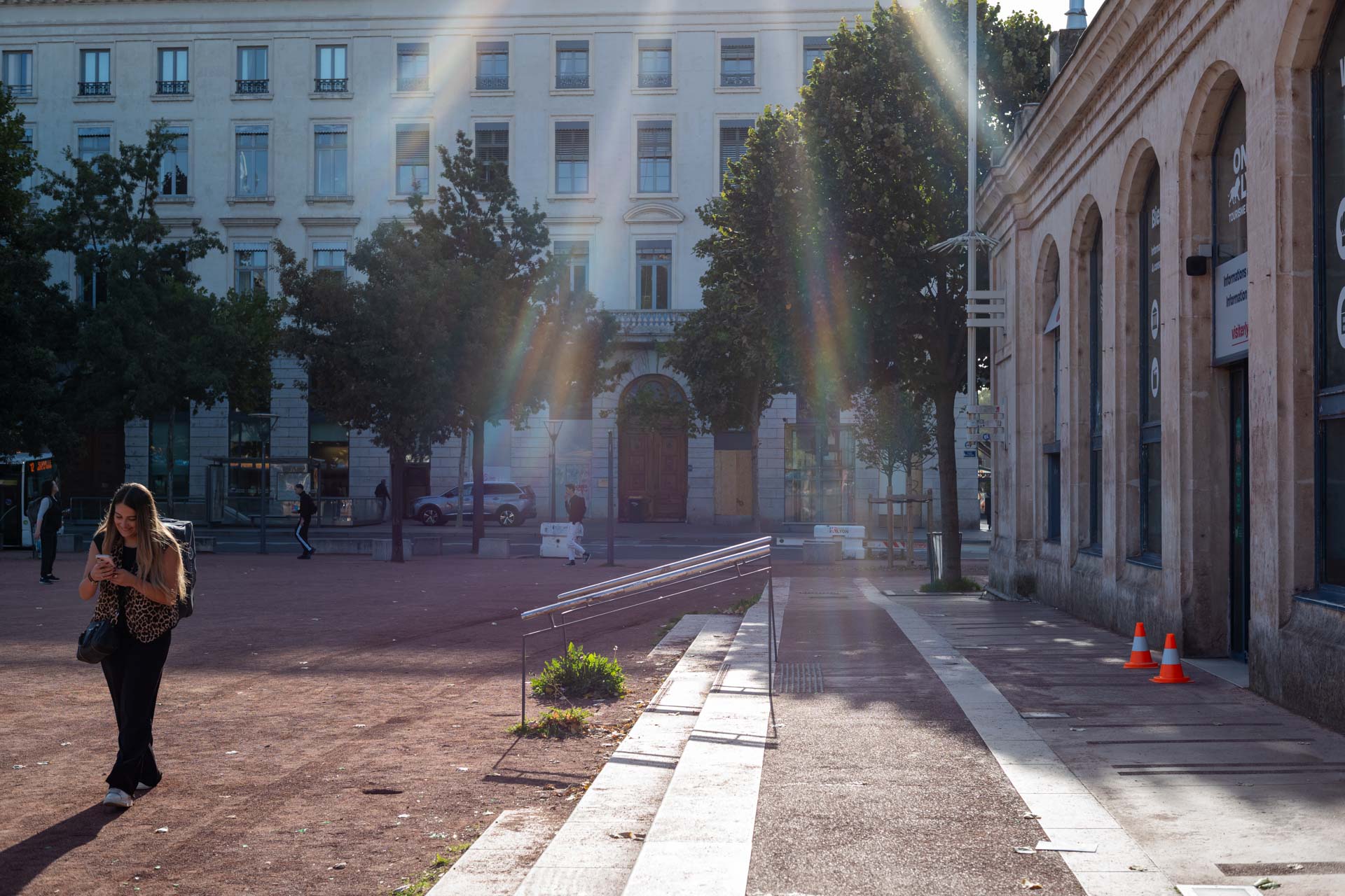 Beispielfoto mit Thypoch Simera 50/1.4: Sonnenstrahlen erfassen einen Passanten auf einem Platz nahe der Touristeninformation von Lyon in Perrache, Lyon, Frankreich.