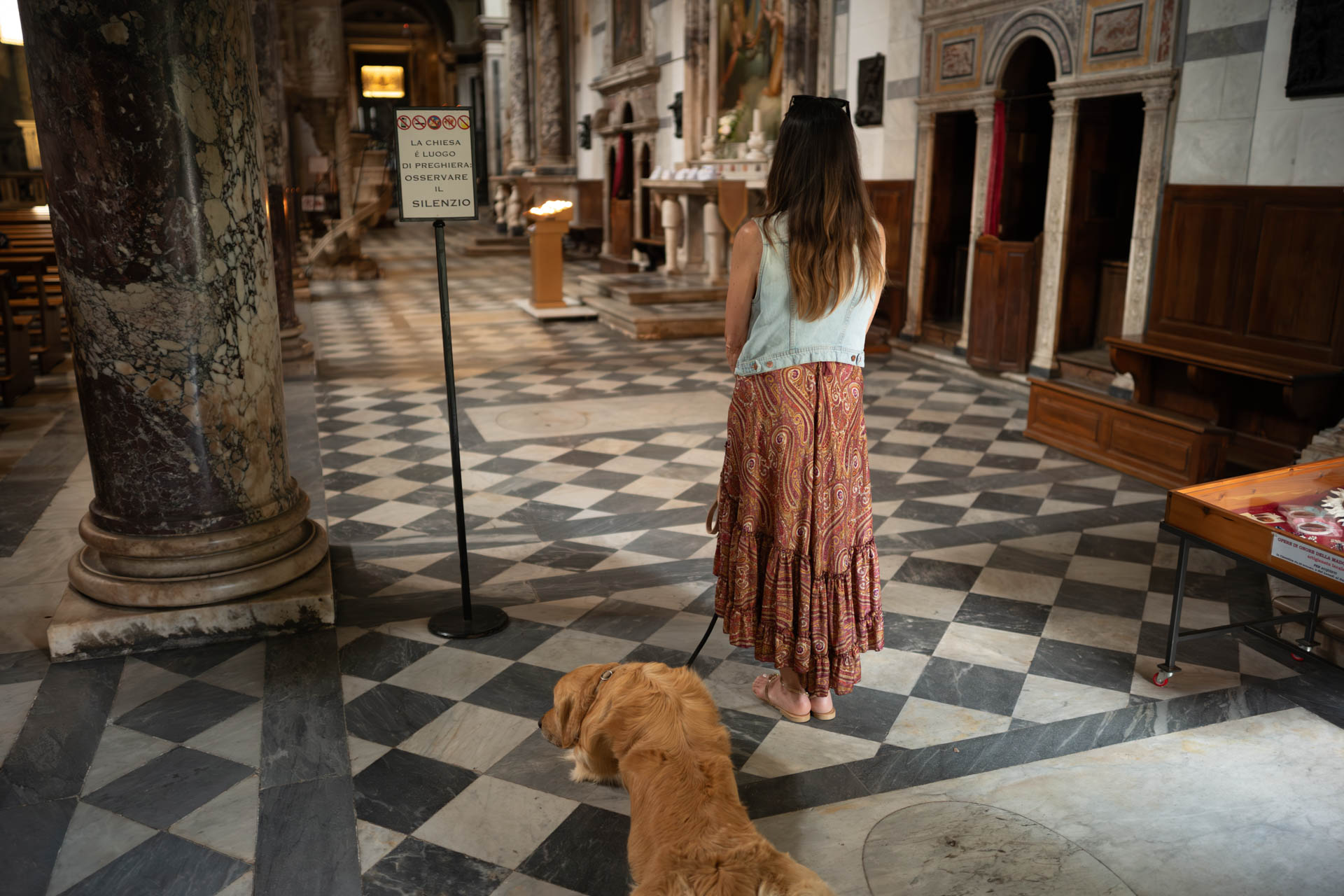 Beispielfoto mit Thypoch Simera 50/1.4: eine Frau mit ihrem Golden Retriever auf dem karierten Marmorboden einer Kirche in Camaiore (Provinz Lucca), Italien.